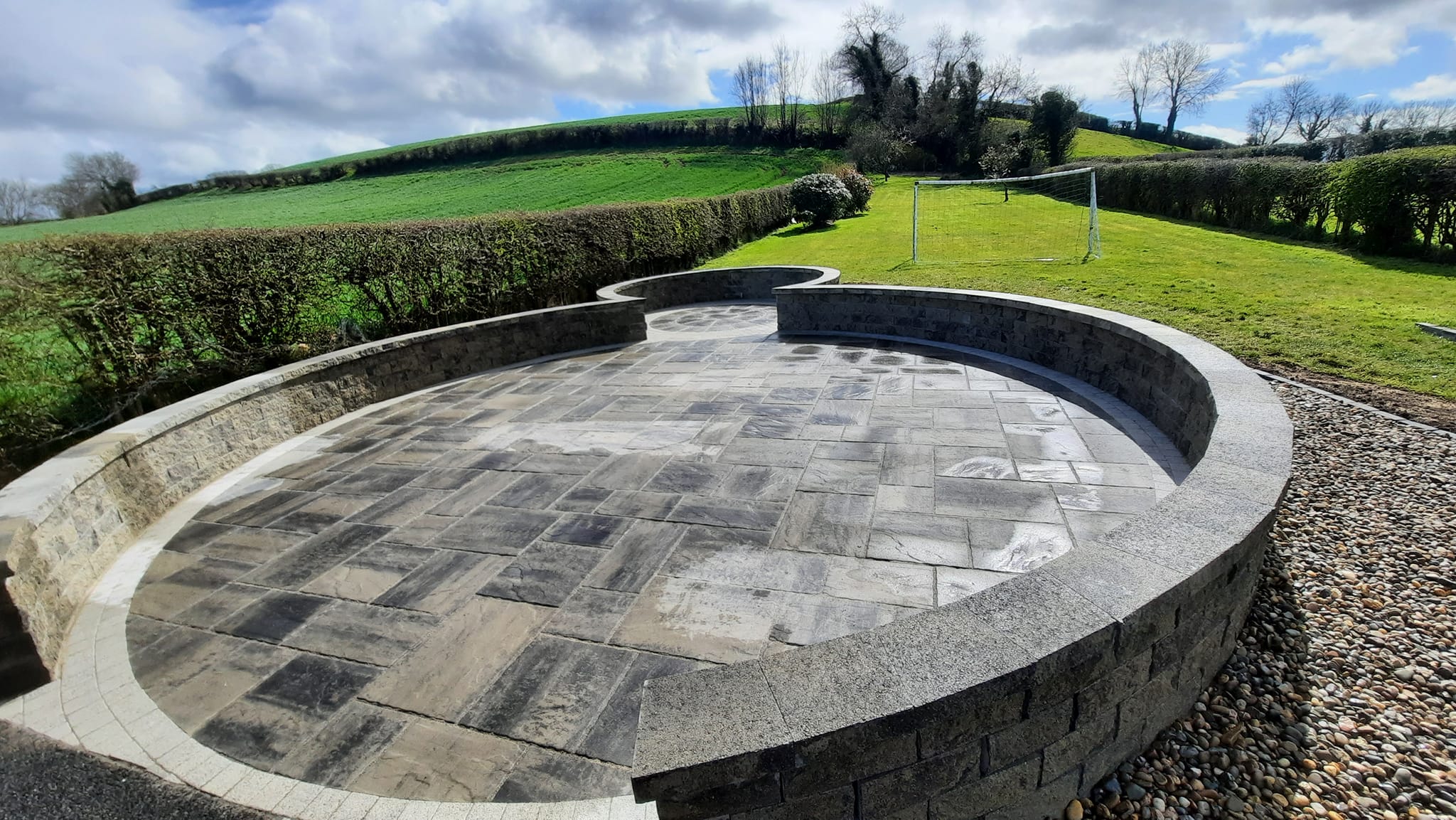 enclosed circular paved patio in a grass back garden