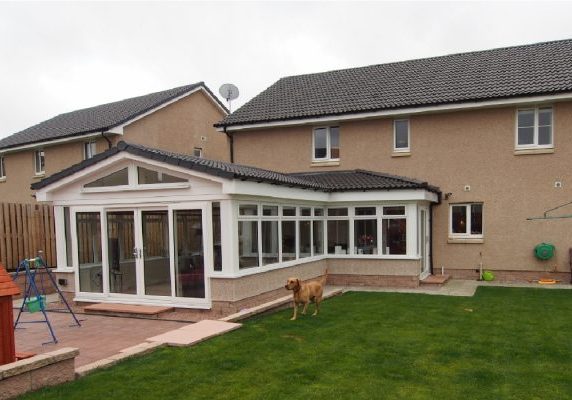 L shaped extension at the back of the house with dog running around the garden